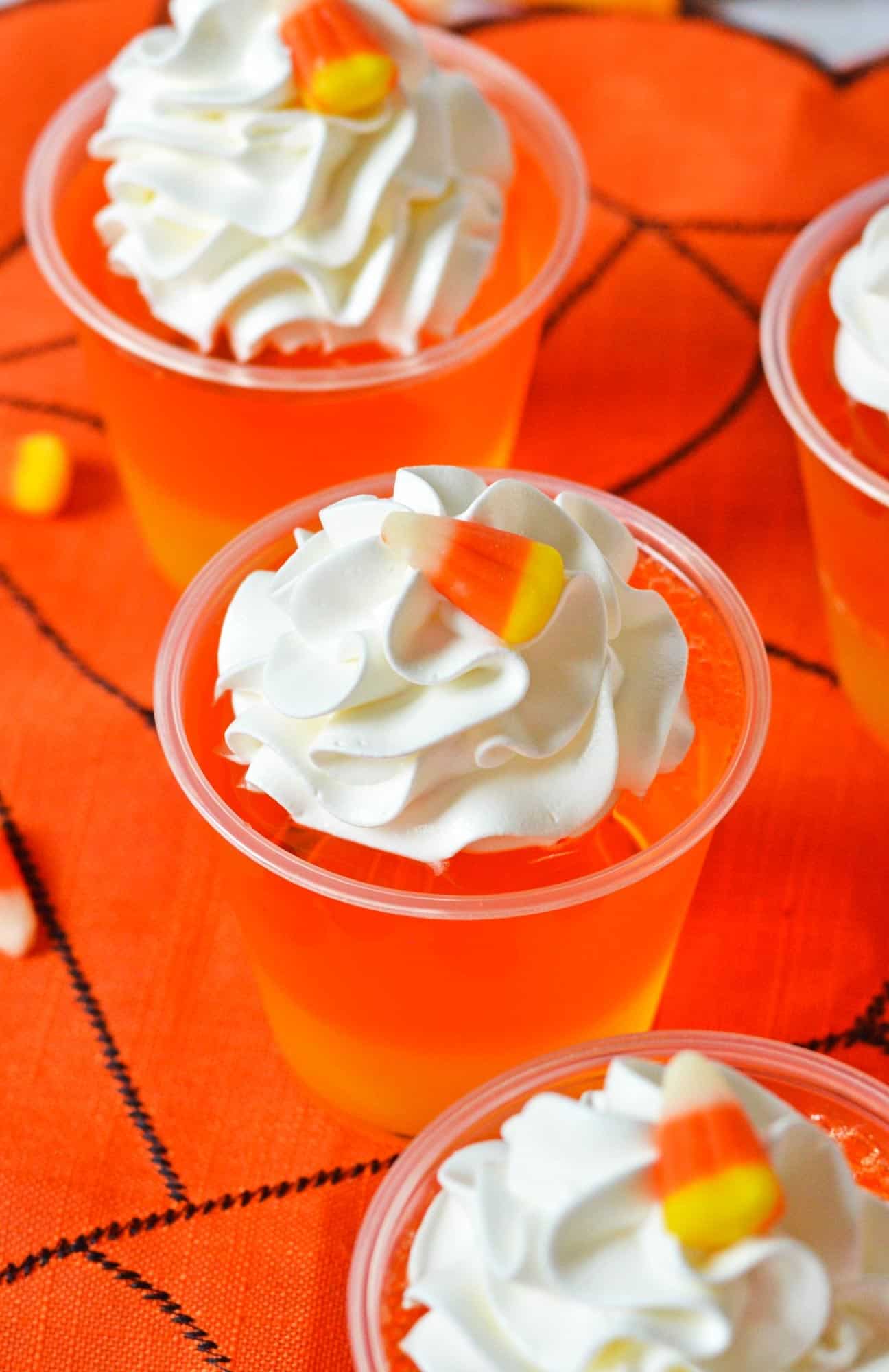 candy corn jello cups on a halloween tablecloth, viewed from overhead