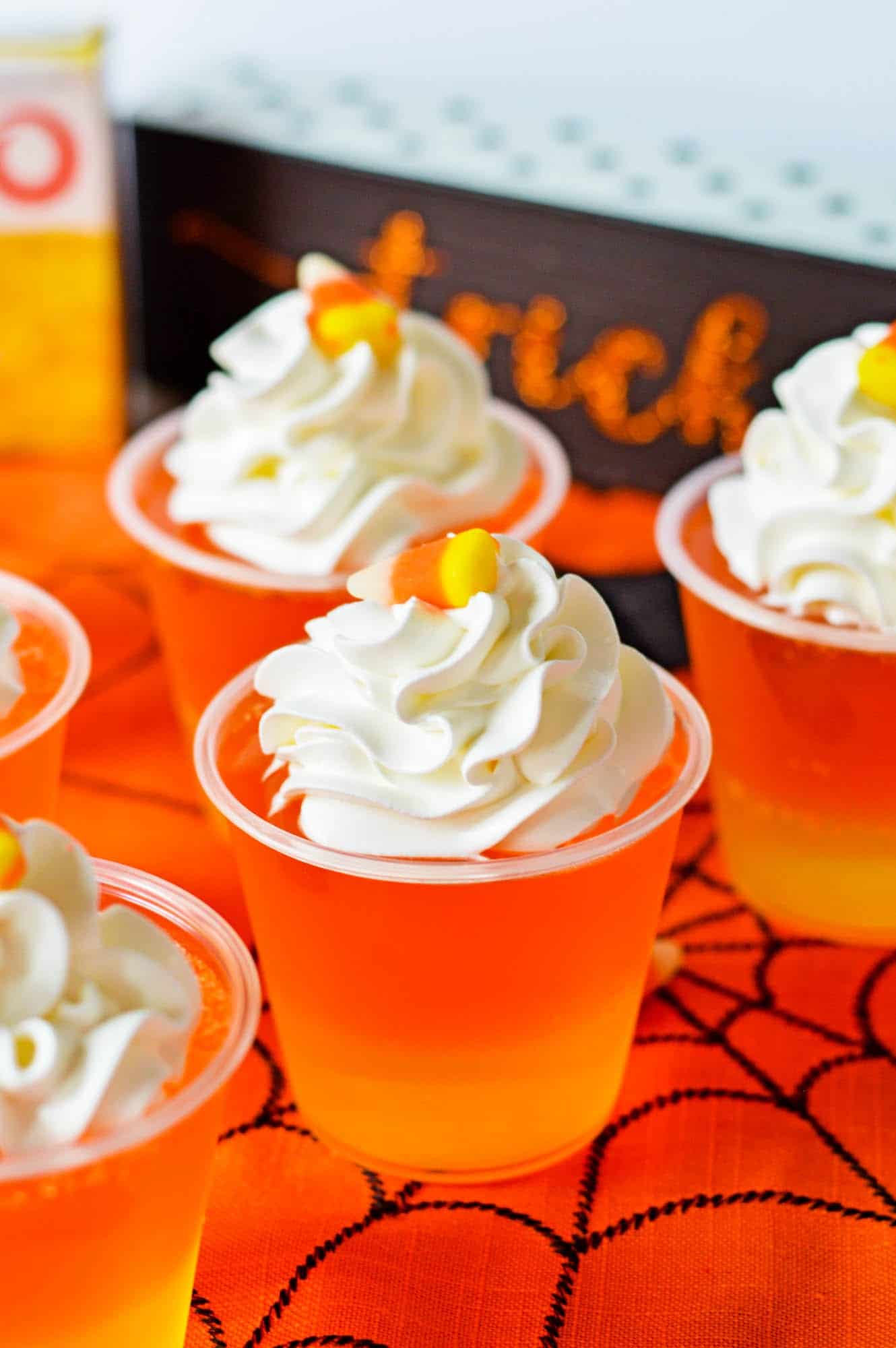 cups of candy corn jello next to halloween decorations