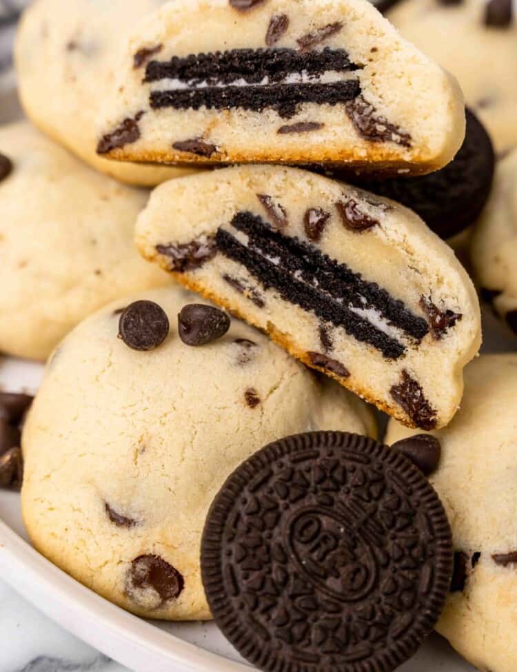 Thick chocolate chip cookies with Oreos inside. One is cut in half to show what it looks like in the middle.