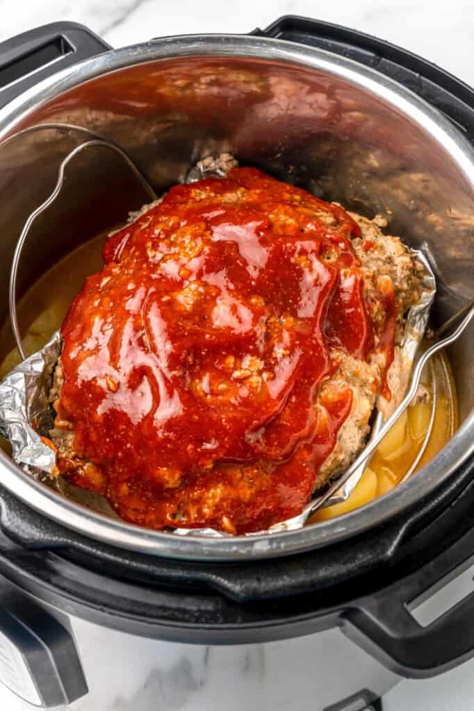a glazed meatloaf being lifted out of an instant pot