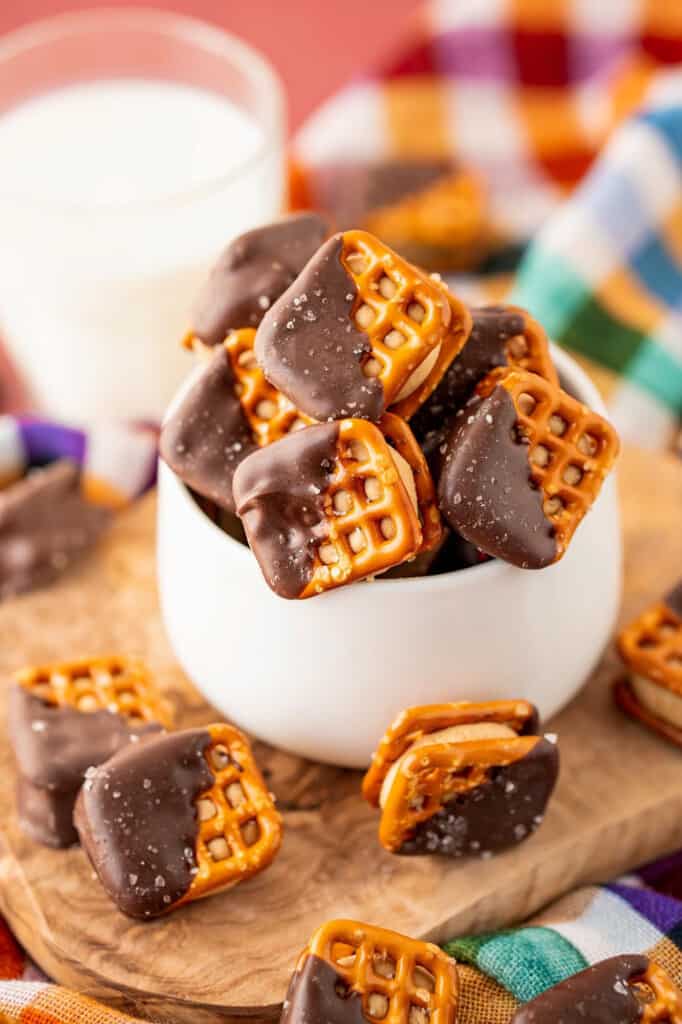 Chocolate peanut butter pretzel bites in a small white bowl, with a glass of milk in the background.