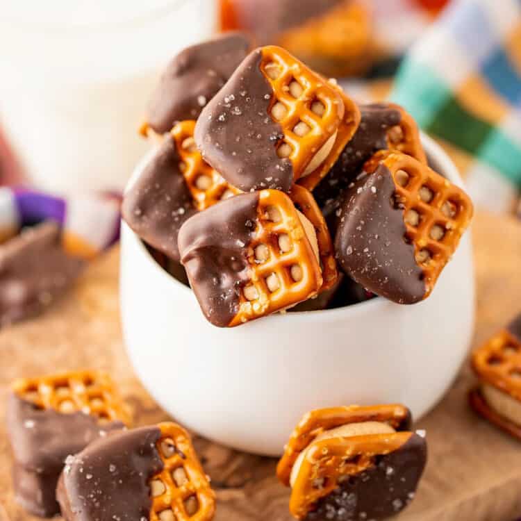 Chocolate peanut butter pretzel bites in a small white bowl, with a glass of milk in the background.