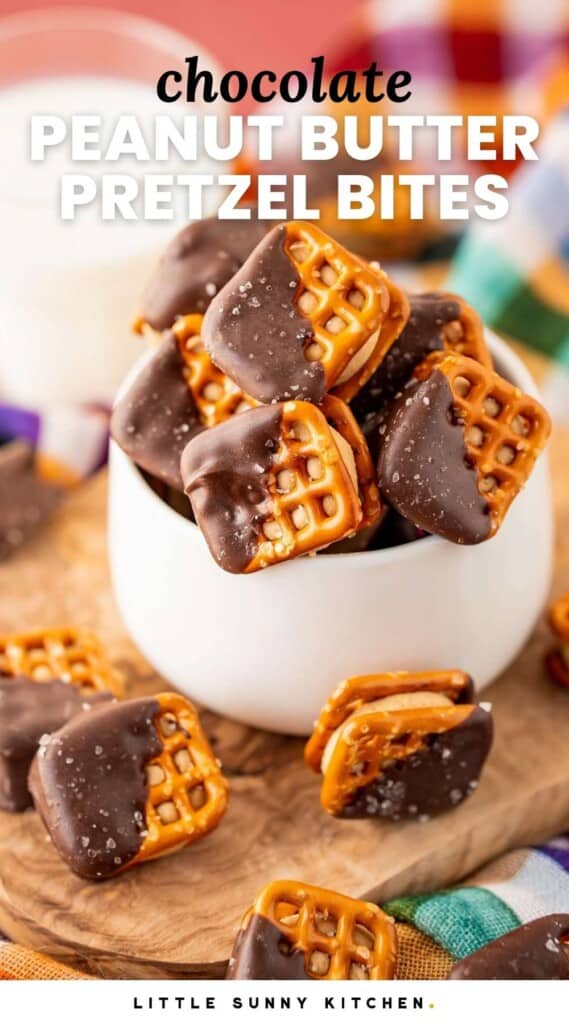 Chocolate peanut butter pretzel bites in a small white bowl, with a glass of milk in the background. And overlay text that says "chocolate peanut butter pretzel bites"