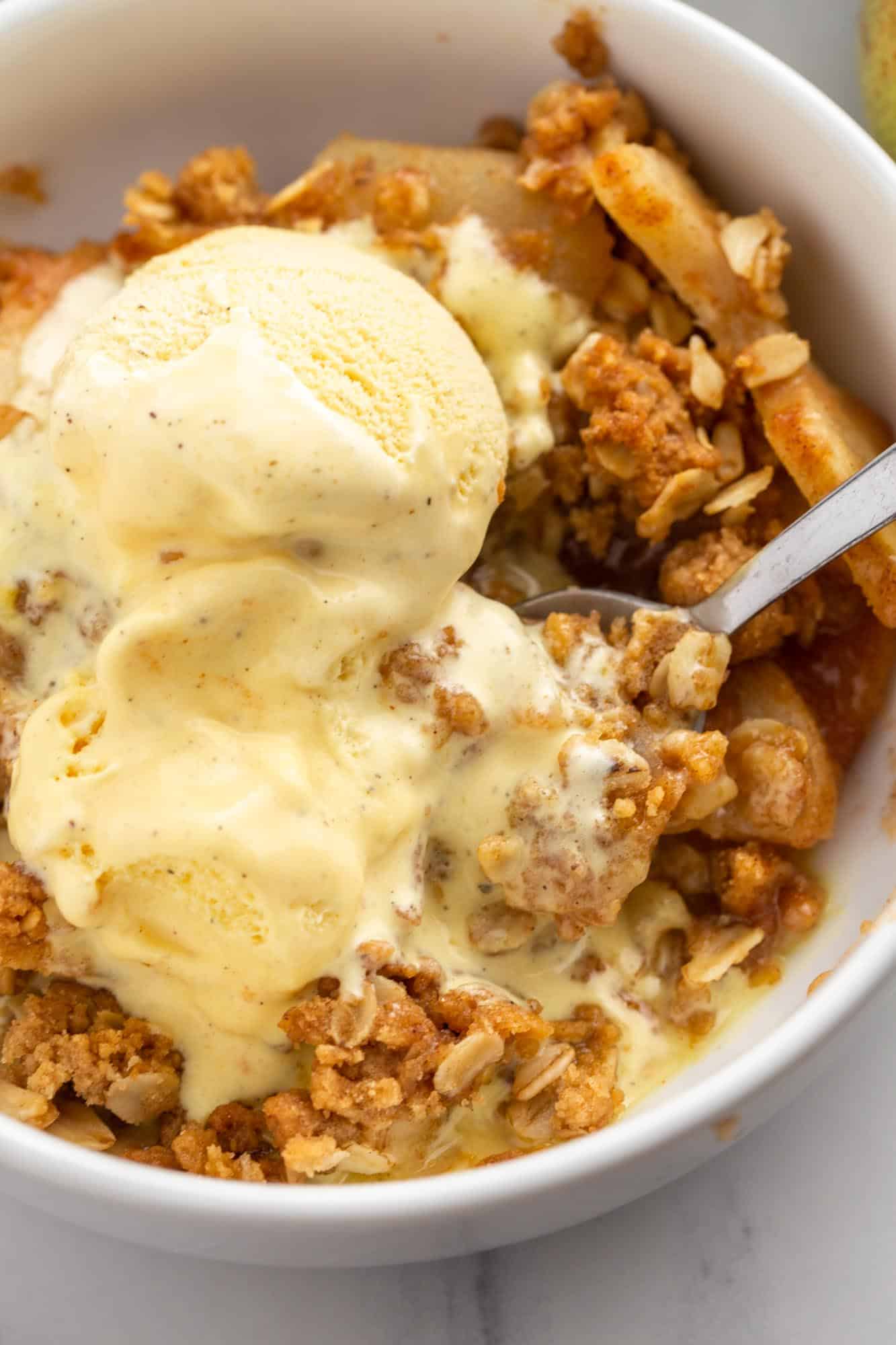 a bowl of pear crisp topped with scoops of vanilla ice cream