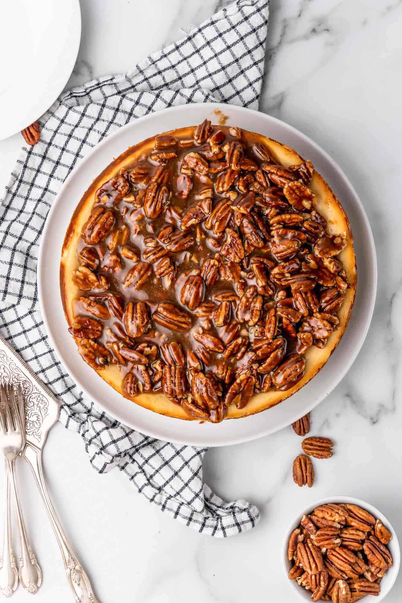 a pecan pie cheesecake on top of a blue and white checked towel, viewed from overhead
