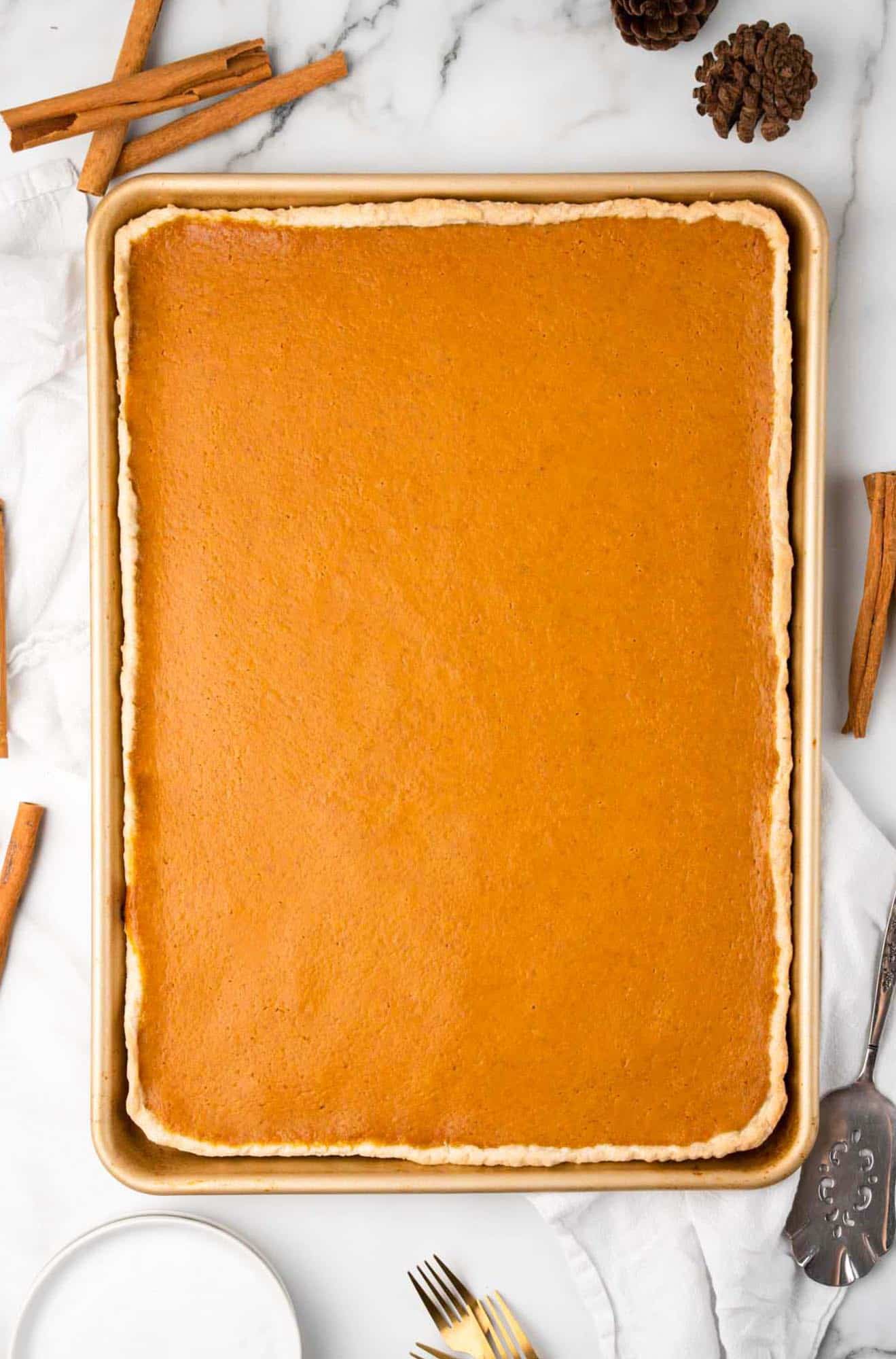 a baked pumpkin sheet pan pie on a marble countertop, viewed from above