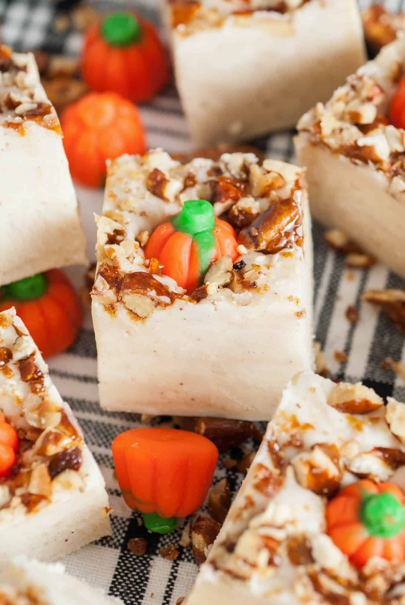 Close up shot of a piece of pumpkin spice fudge with pumpkin candies and pecans