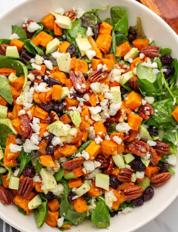 a large bowl filled with greens and a rustic roasted sweet potato salad.