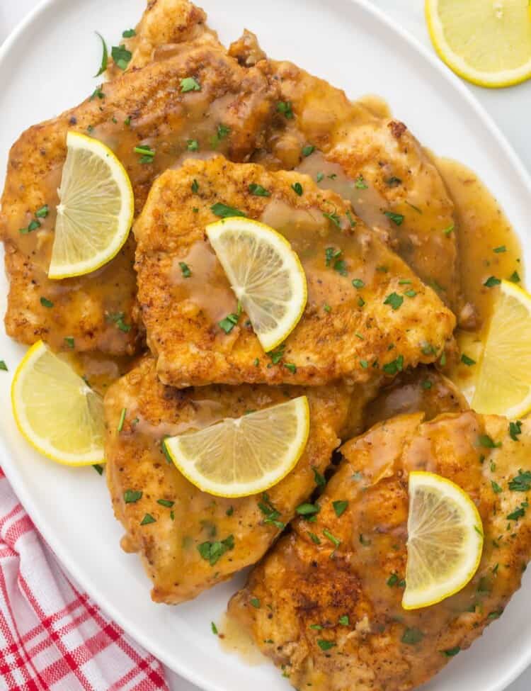 a platter of chicken francese cutlets, topped with thin half slices of lemon.
