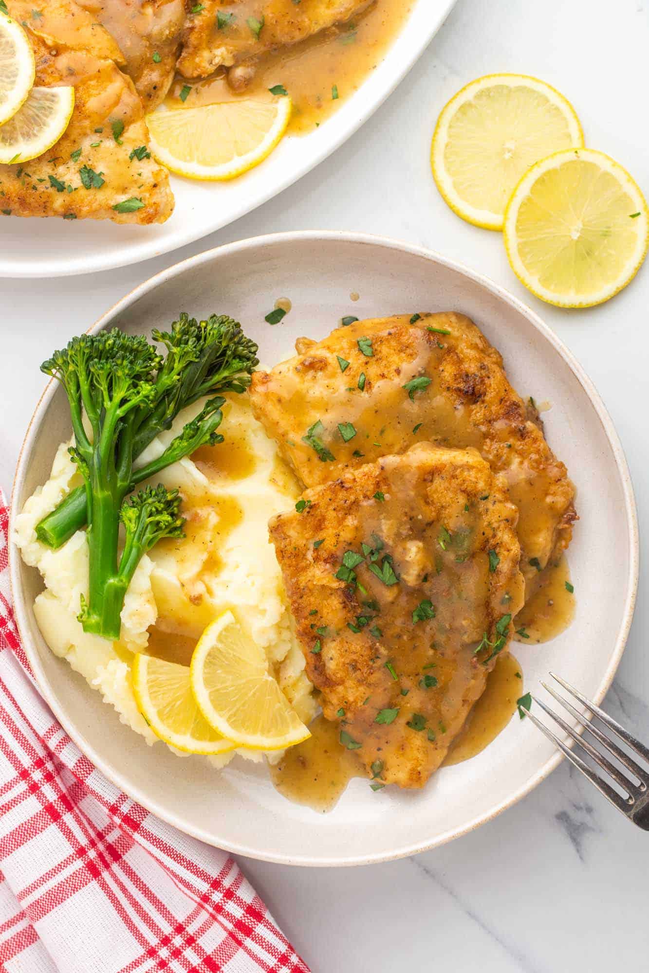 a dinner plate of chicken francese with mashed potatoes and broccolini on the side. 