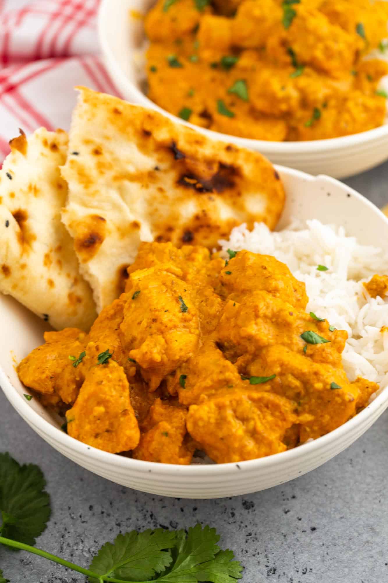 A bowl of chicken korma over rice with torn pita bread on the side. 
