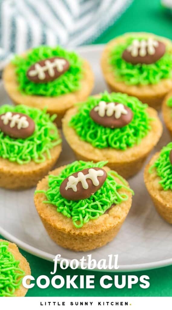 Football cookie cups with chocolate almonds and green buttercream grass, served on a plate that is placed on a green background. And overlay text that says "football cookie cups"