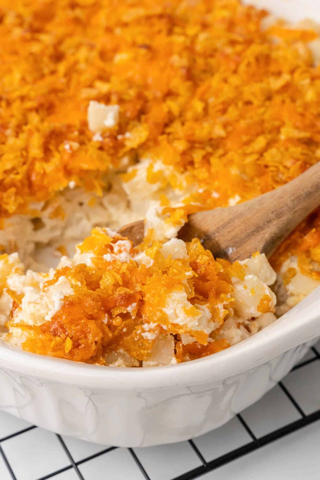 a white casserole dish filled with funeral potatoes with a cornflake topping