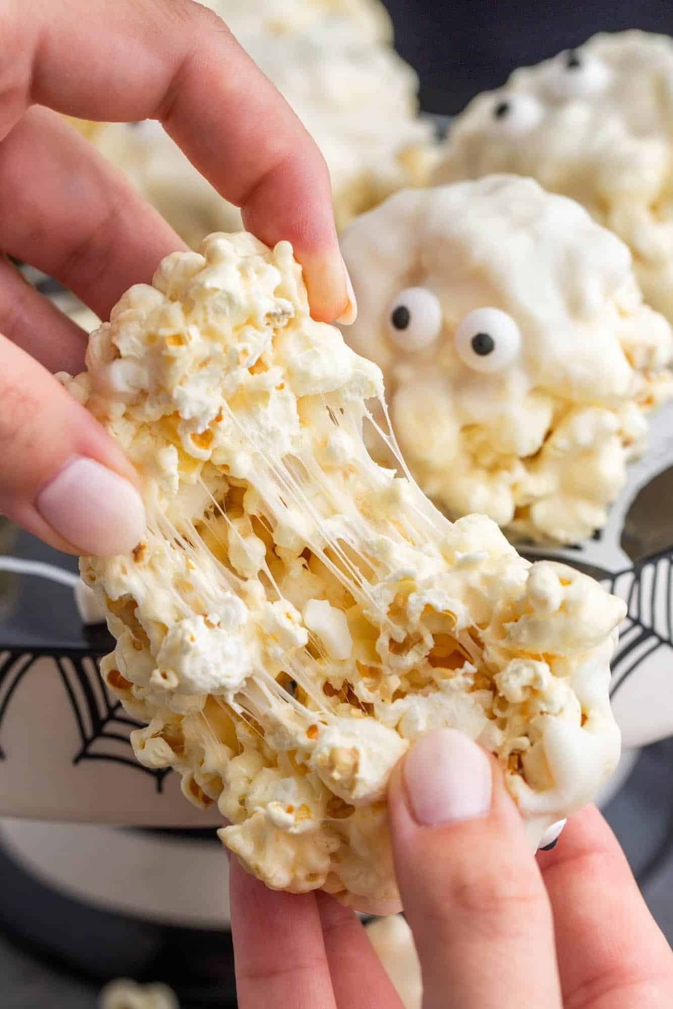 a soft and sticky popcorn ball being pulled apart by two feminine hands 
