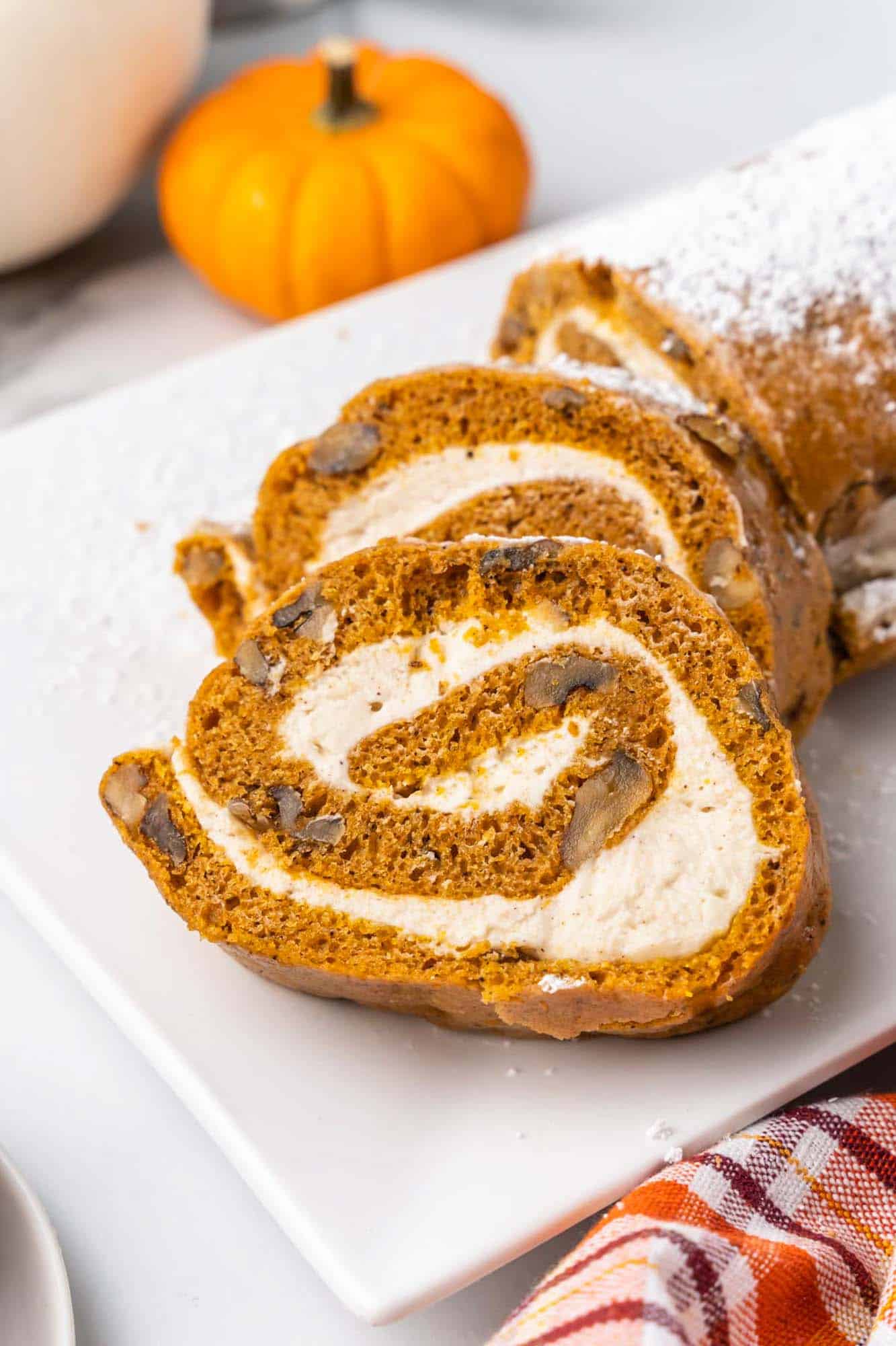 Slices of pumpkin roll on a square white plate. 