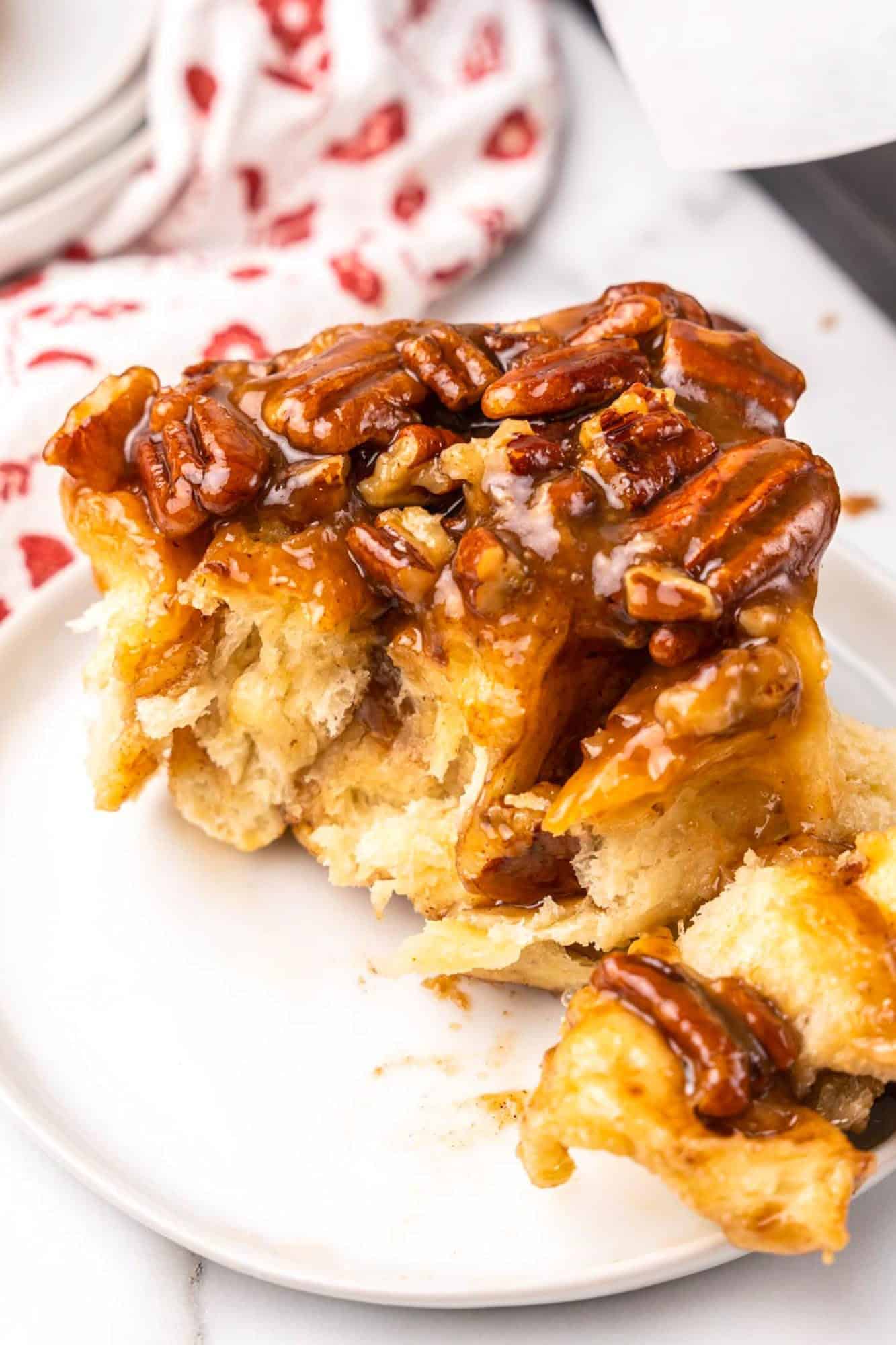 a fluffy pecan roll sticky bun on a small white plate. 
