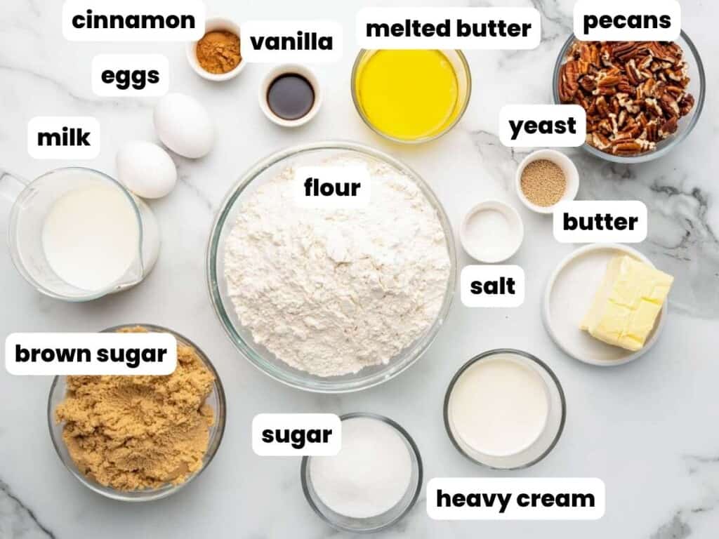 The ingredients needed to make a sticky buns recipe, all measured into small bowls, and arranged on the counter. Text overlays label each ingredient. 