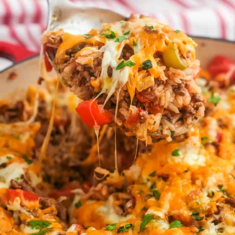 stuffed pepper casserole in a skillet. A spoon is lifting up a serving showing melty cheese.