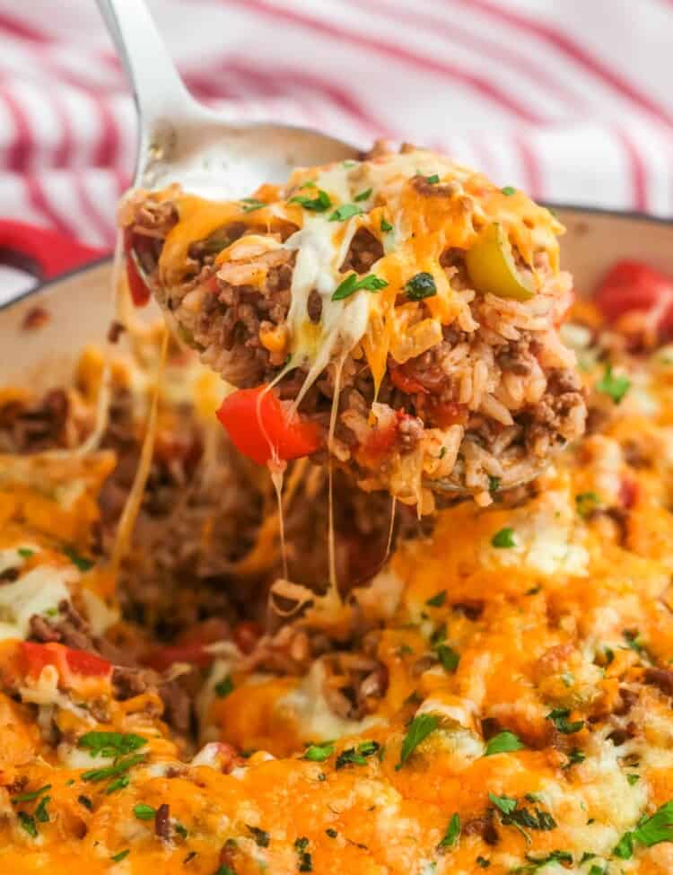stuffed pepper casserole in a skillet. A spoon is lifting up a serving showing melty cheese.
