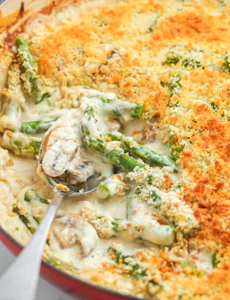 creamy cheesy asparagus casserole topped with panko bread crumbs in an enameled skillet.