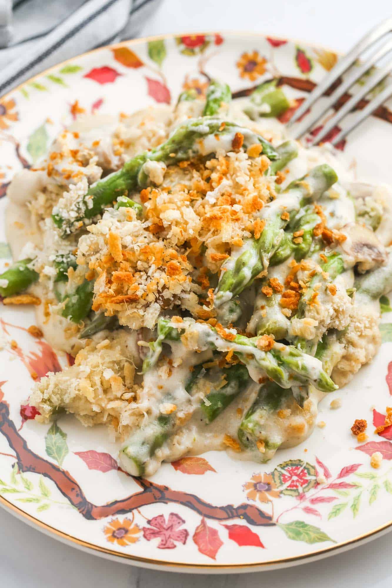 a serving of cheesy asparagus bake on a patterned plate. A fork is on the edge of the plate.
