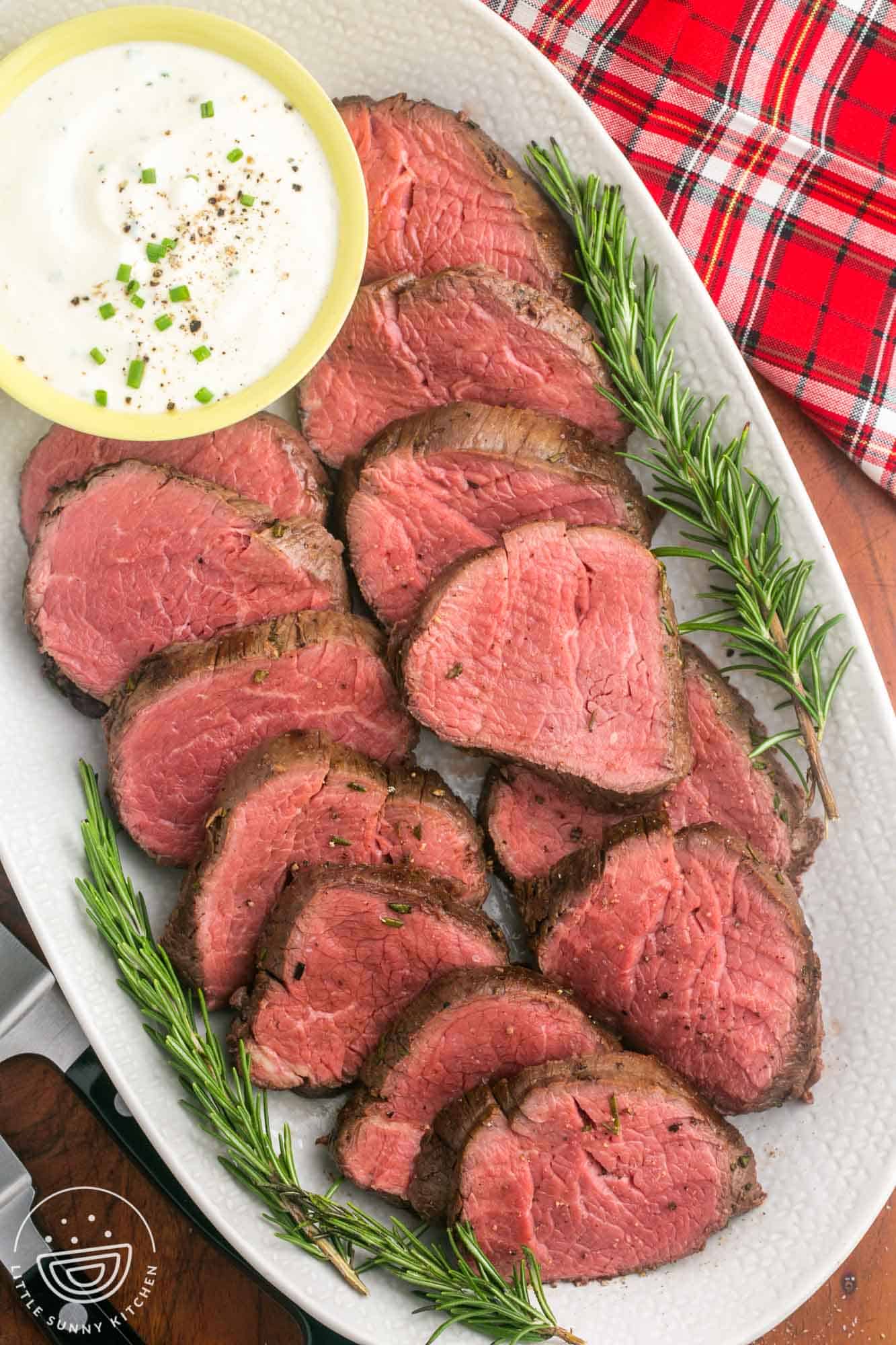 Large oval platter with beef tenderloin slices, and a bowl of horseradish sauce