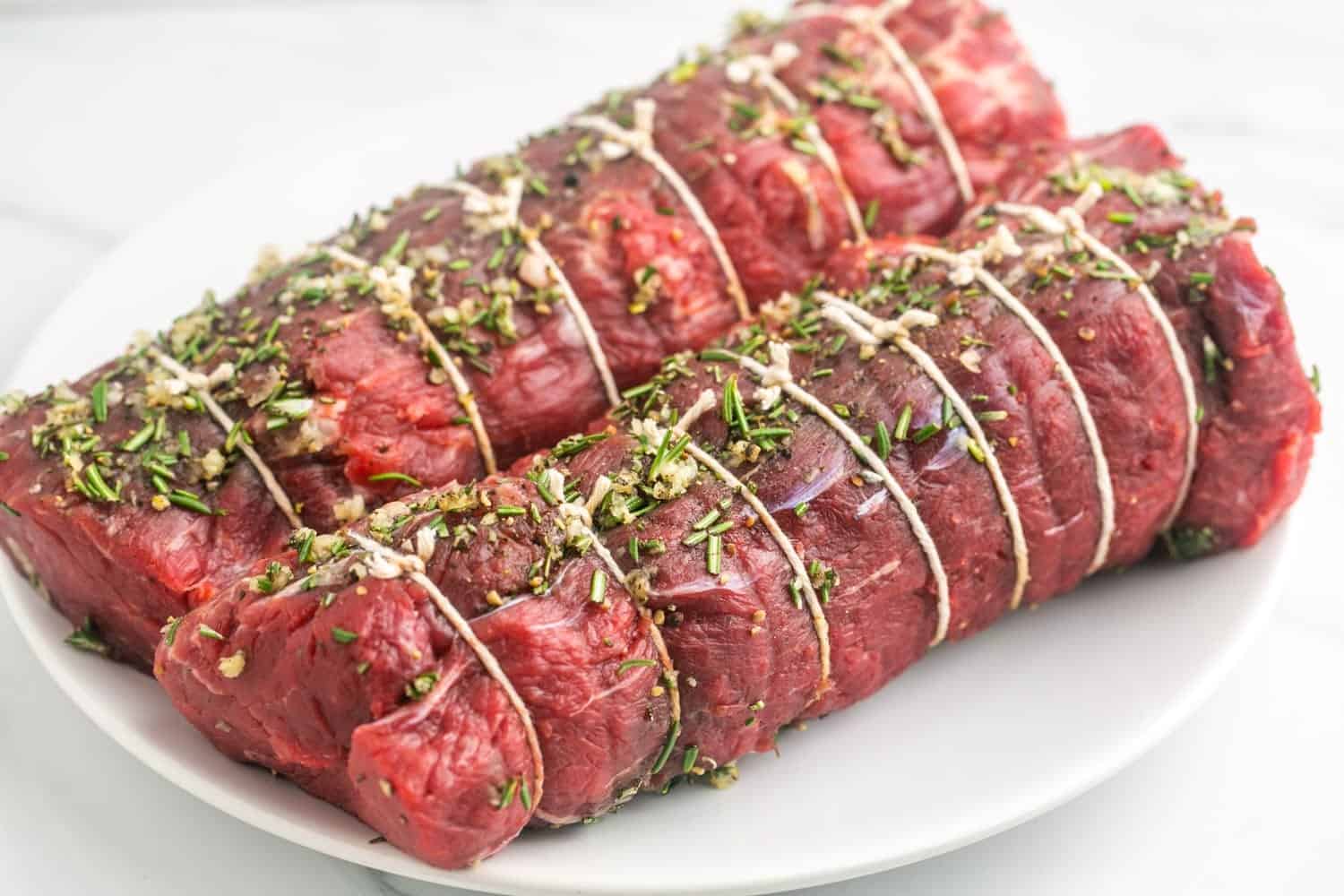 2 pieces of beef tenderloin seasoned with garlic, rosemary, salt and pepper and trussed with kitchen twine.