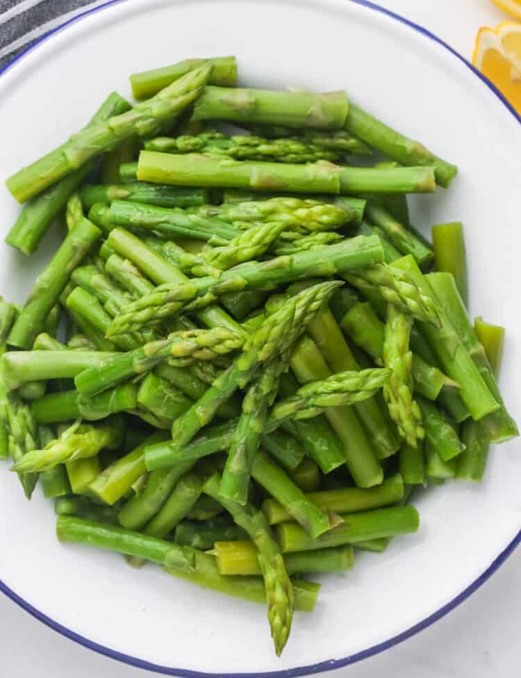 blanched asparagus pieces on a plate, overhead shot.