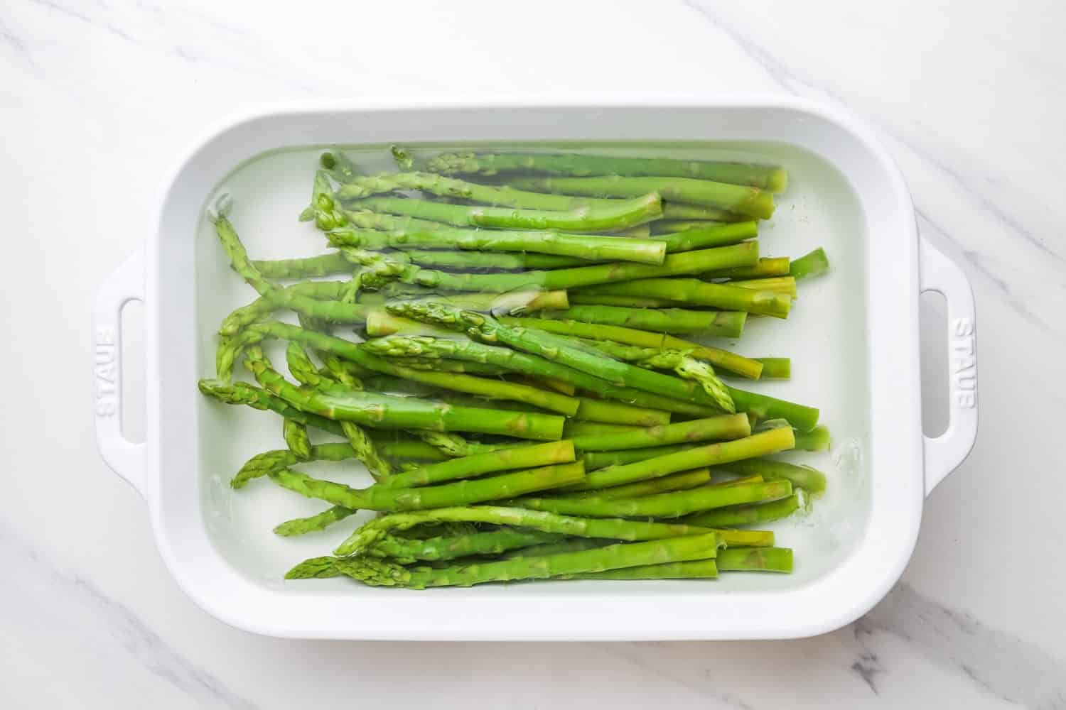 Plunging blanched asparagus in ice water in a staub dish
