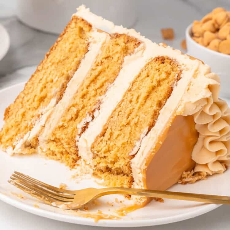 a large wedge slice of a three layer butterscotch cake, on its side on a plate. A fork is on the plate.