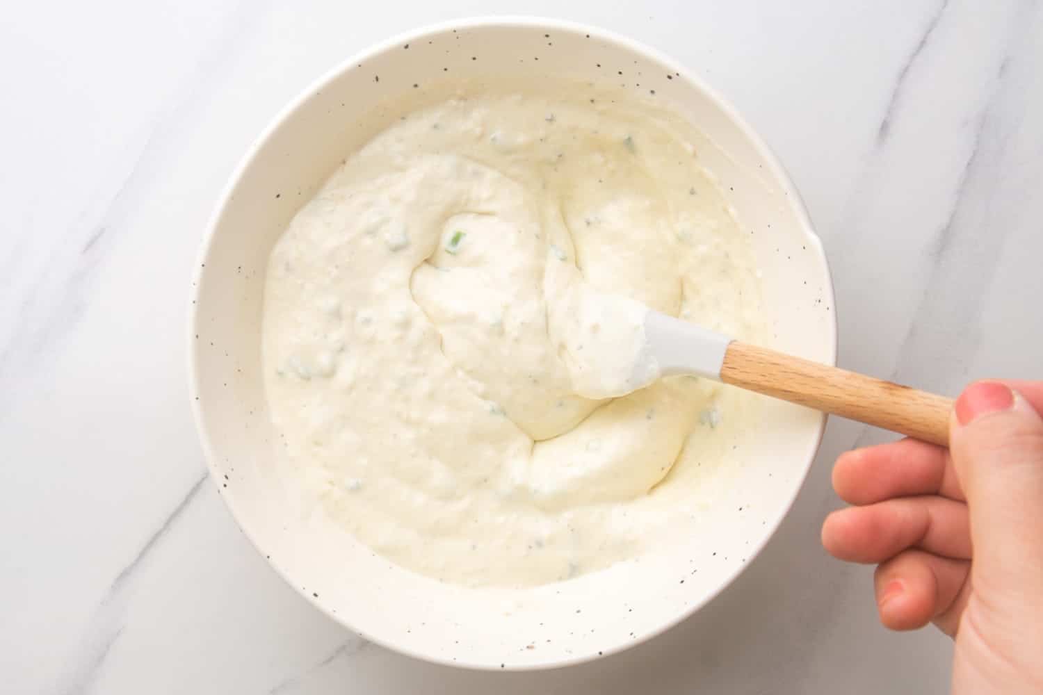 Mixing up the horseradish cream sauce ingredients in a white bowl
