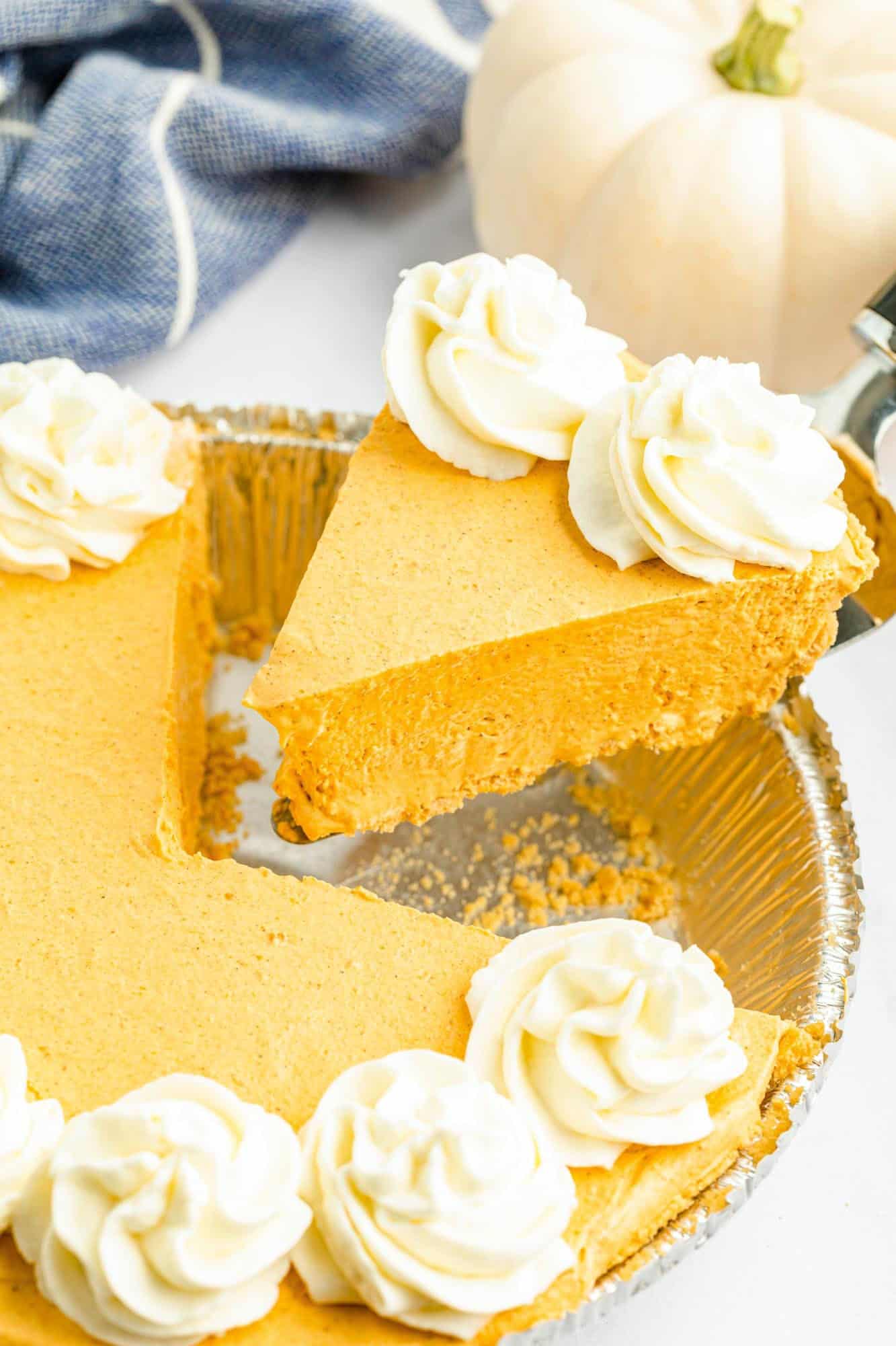 a large slice of pumpkin pudding no bake pie being lifted out of a foil pan. 