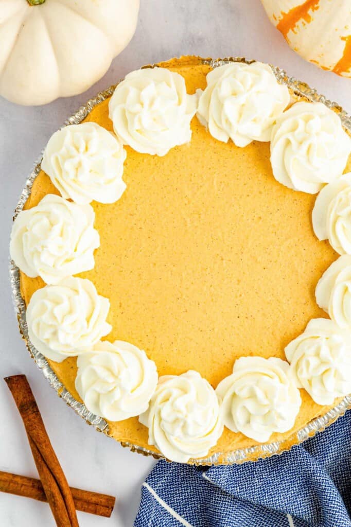 a whole no bake pumpkin pie viewed from above. Large mounds of whipped cream are piped around the edge