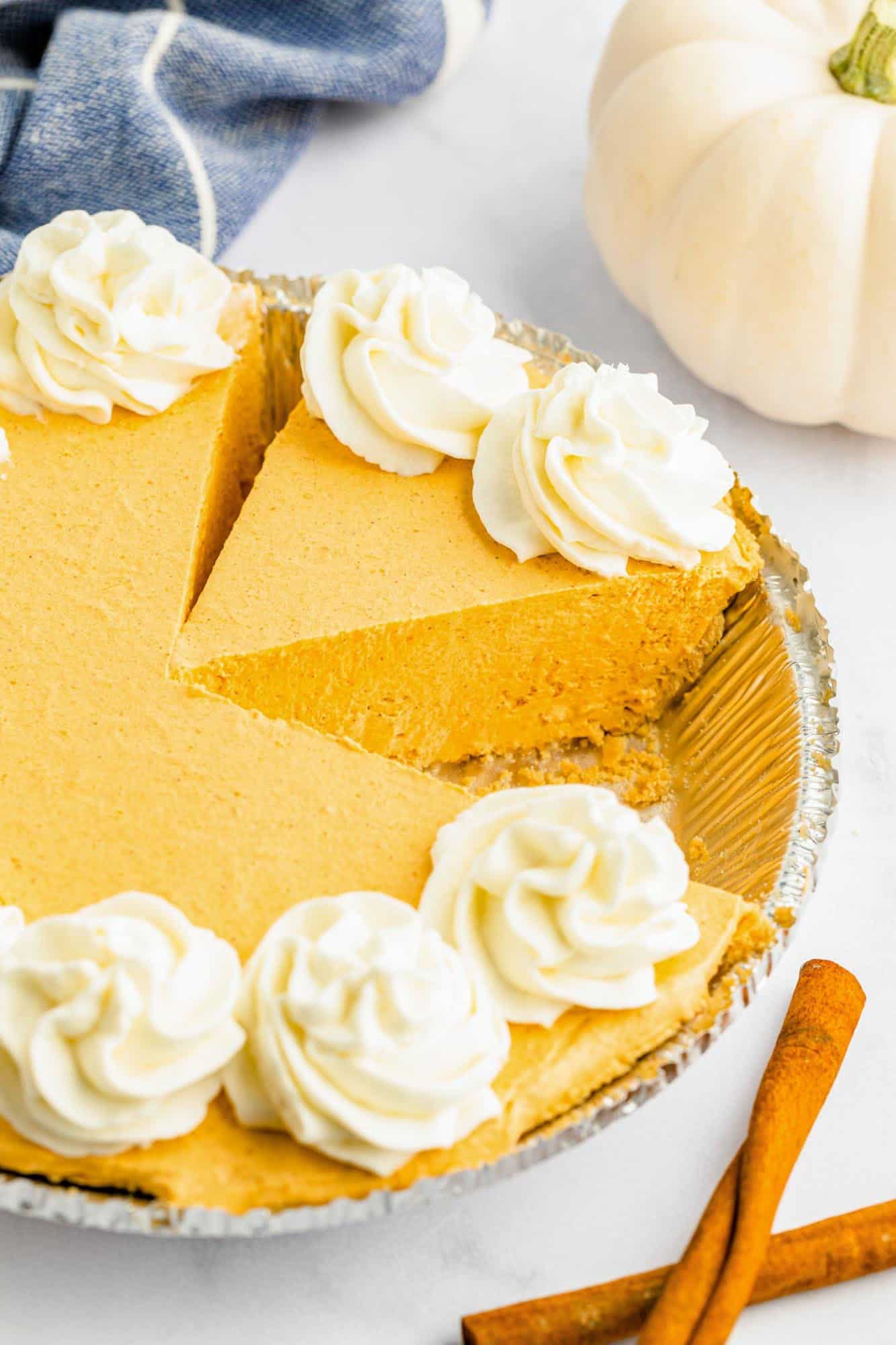 a no bake pumpkin pie in a graham cracker crust metal tin. The pie has a slice removed. 