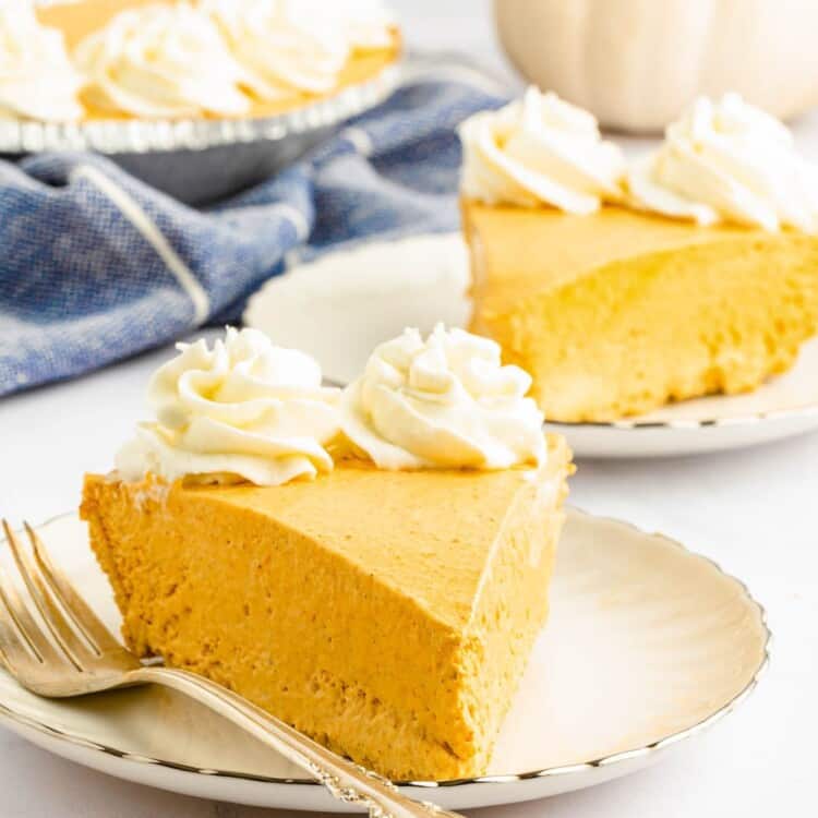 a slice of creamy no bake pumpkin pie topped with whipped cream rosettes, on a dessert plate with a fork.
