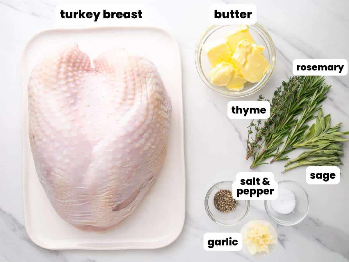 a raw turkey breast on a rectangular platter. Next to it is a bowl of butter, fresh herbs, garlic, salt, and pepper.