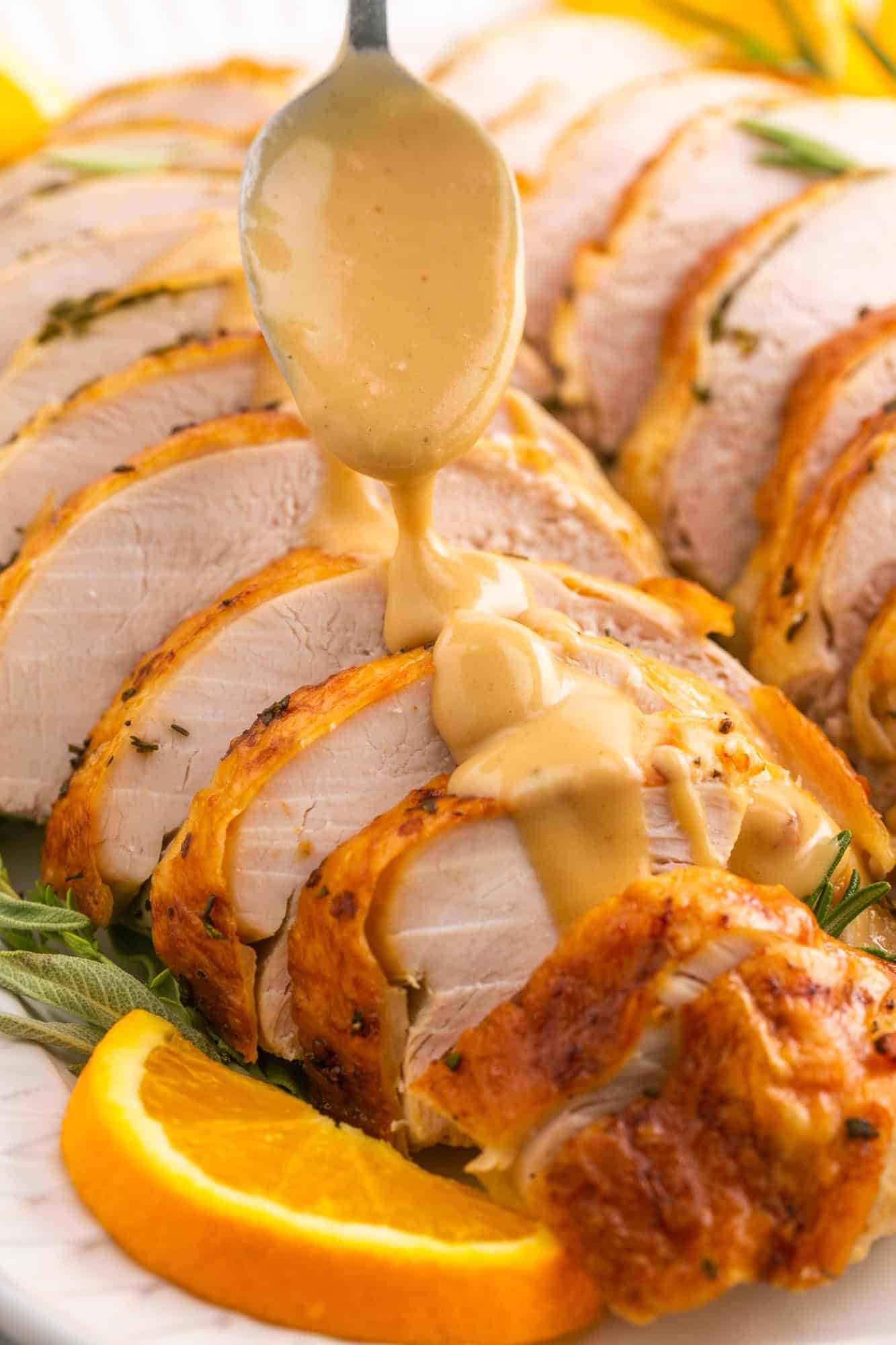 a spoon drizzling gravy over roast turkey breast slices.