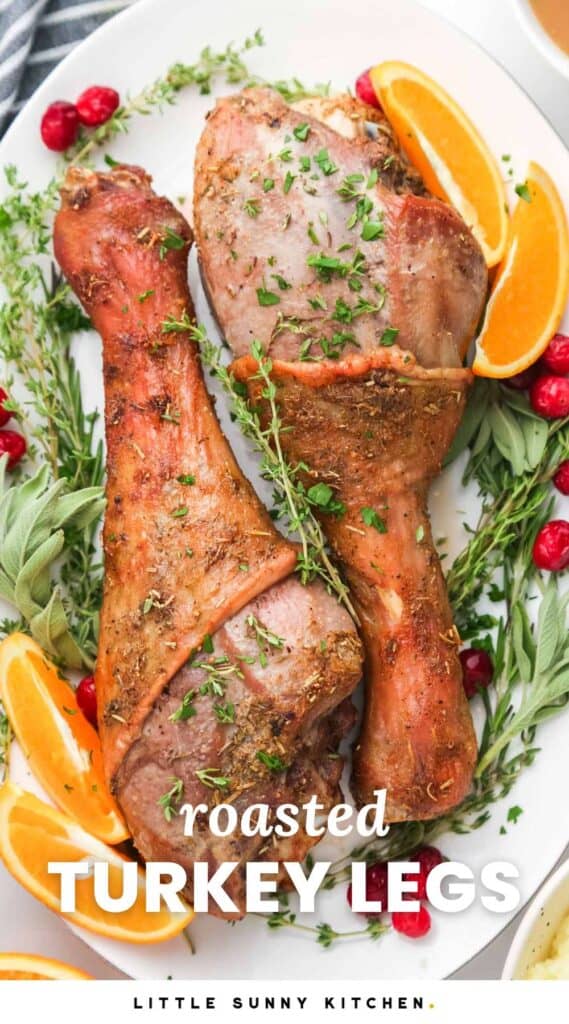 Two large roasted turkey legs on a platter, surrounded by cranberries, fresh herbs, and orange wedges. Text under the image says "roasted turkey legs"