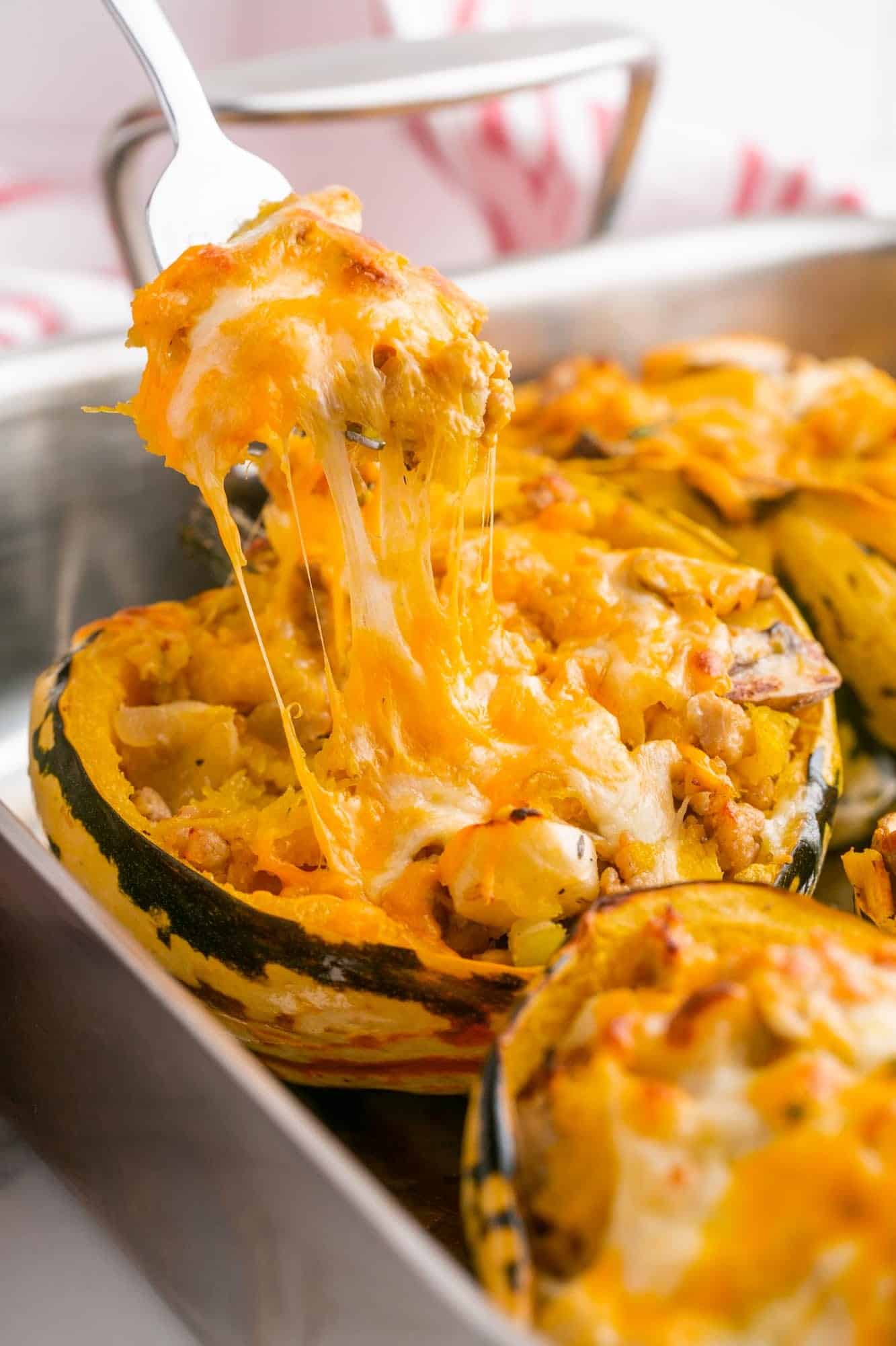 A cheese pull of a stuffed acorn squash using a spoon