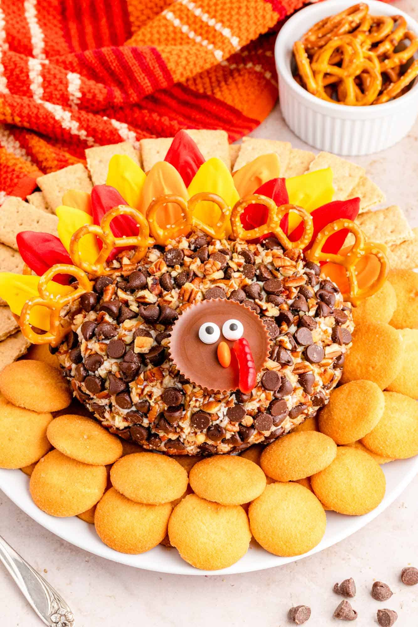 a dessert cheese ball shaped like a turkey with preze and candy melt feathers and a face made from a reeses cup