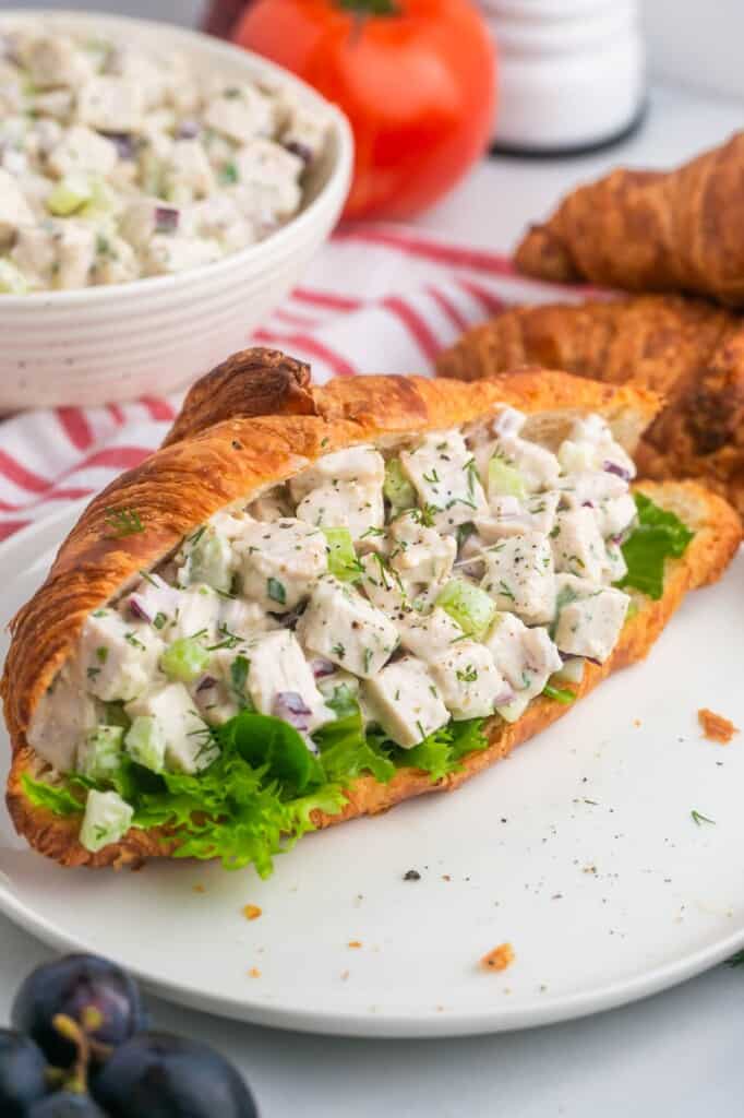 Butter croissant stuffed with turkey salad, placed on a white plate.