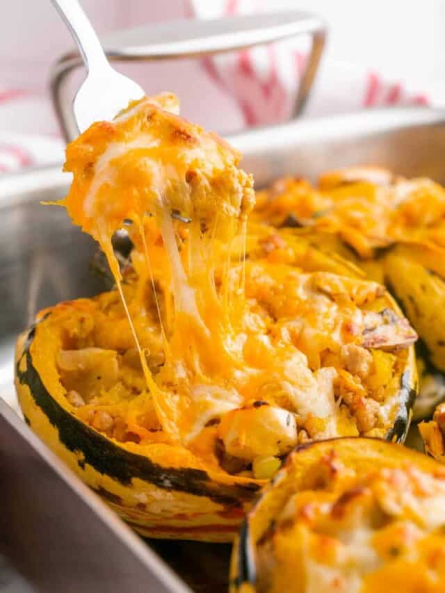 A cheese pull of a stuffed acorn squash using a spoon