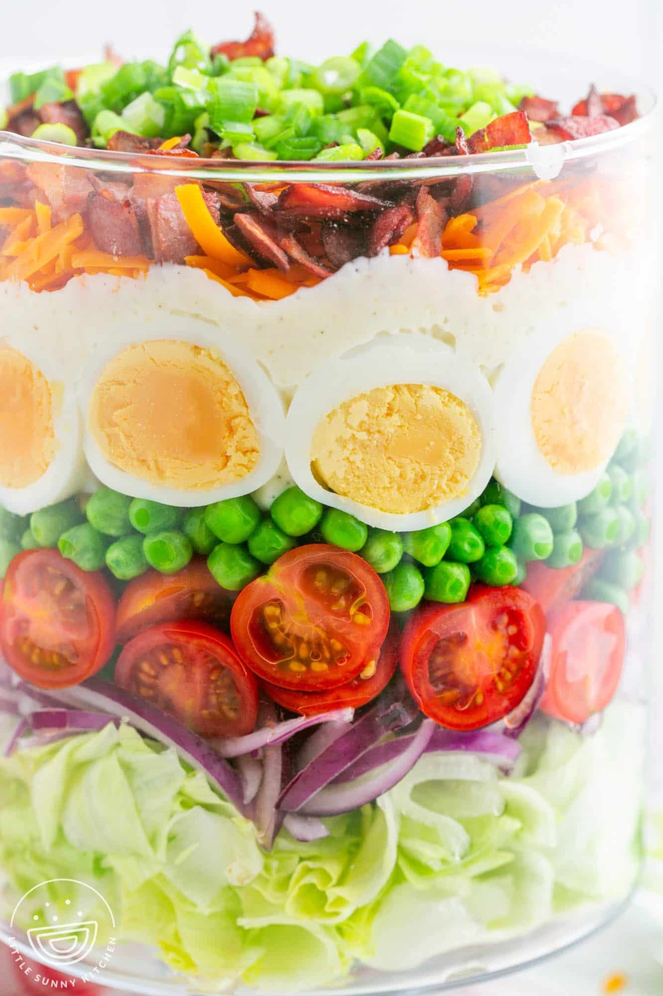 Closeup view of a layered salad in a clear class cylinder dish.