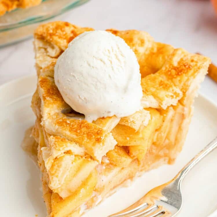 a large slice of apple pie with a lattice top. there's a scoop of ice cream on top of the pie, which is on a plate. there's a fork on the plate.