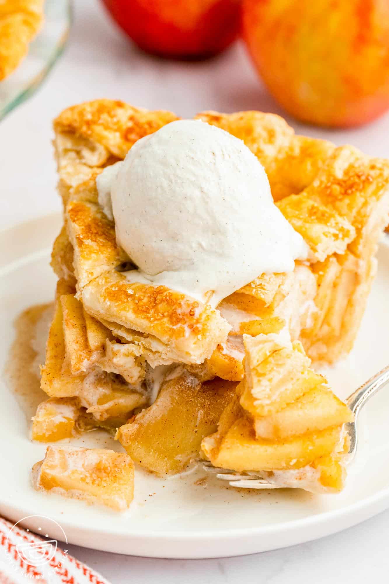 Bite shot of apple pie slice with vanilla ice cream