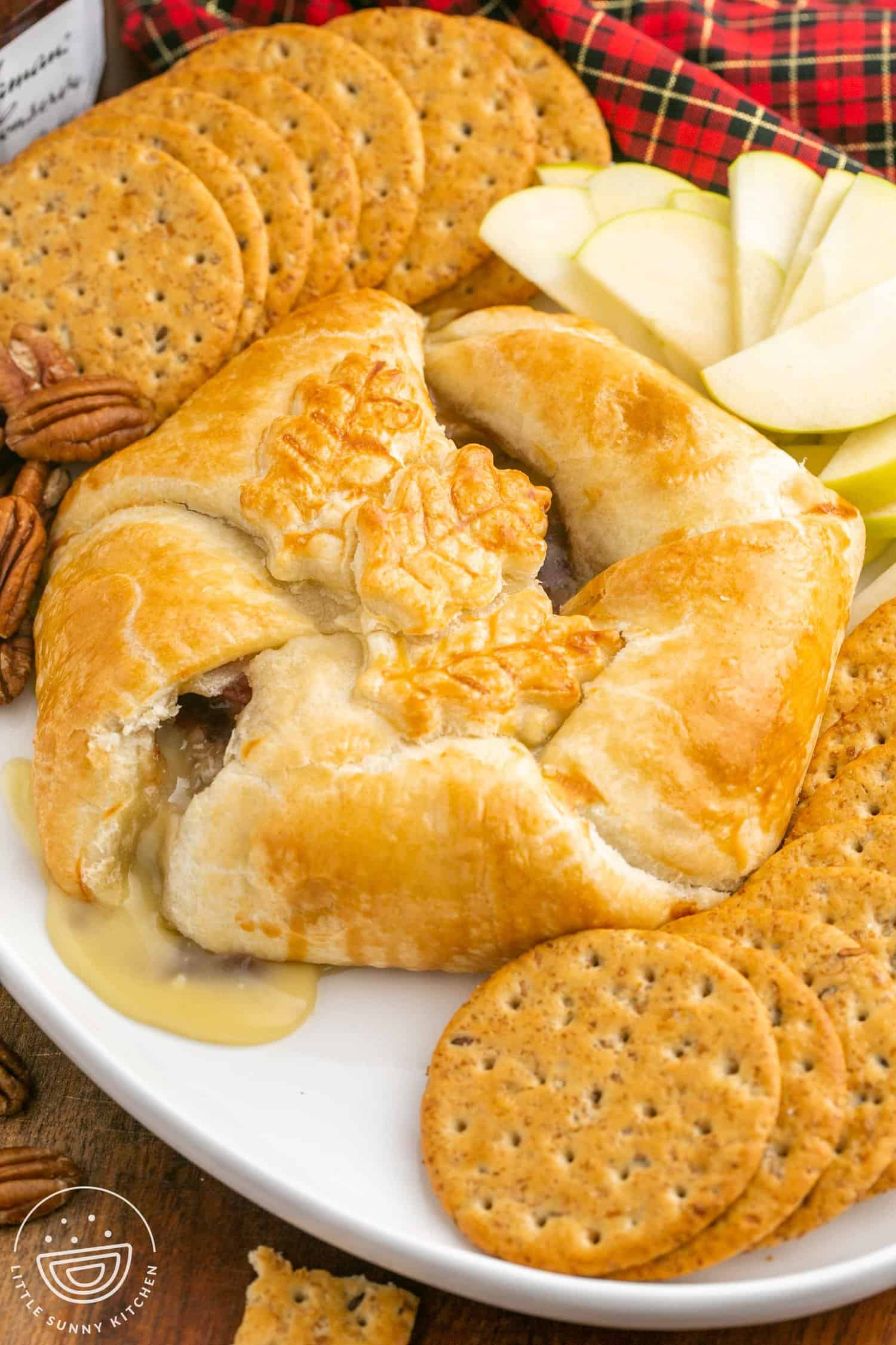 Baked brie in puff pastry served with crackers and thinly sliced apples