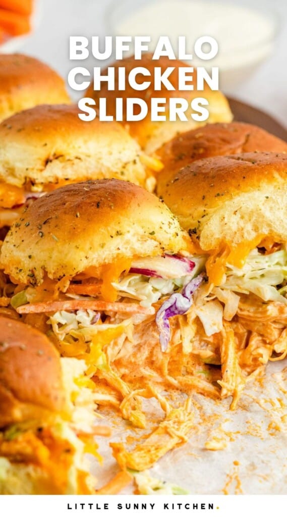 A pan of sliders with buffalo style shredded chicken, and coleslaw on them. Text overlay says "buffalo chicken sliders" in capital letters.
