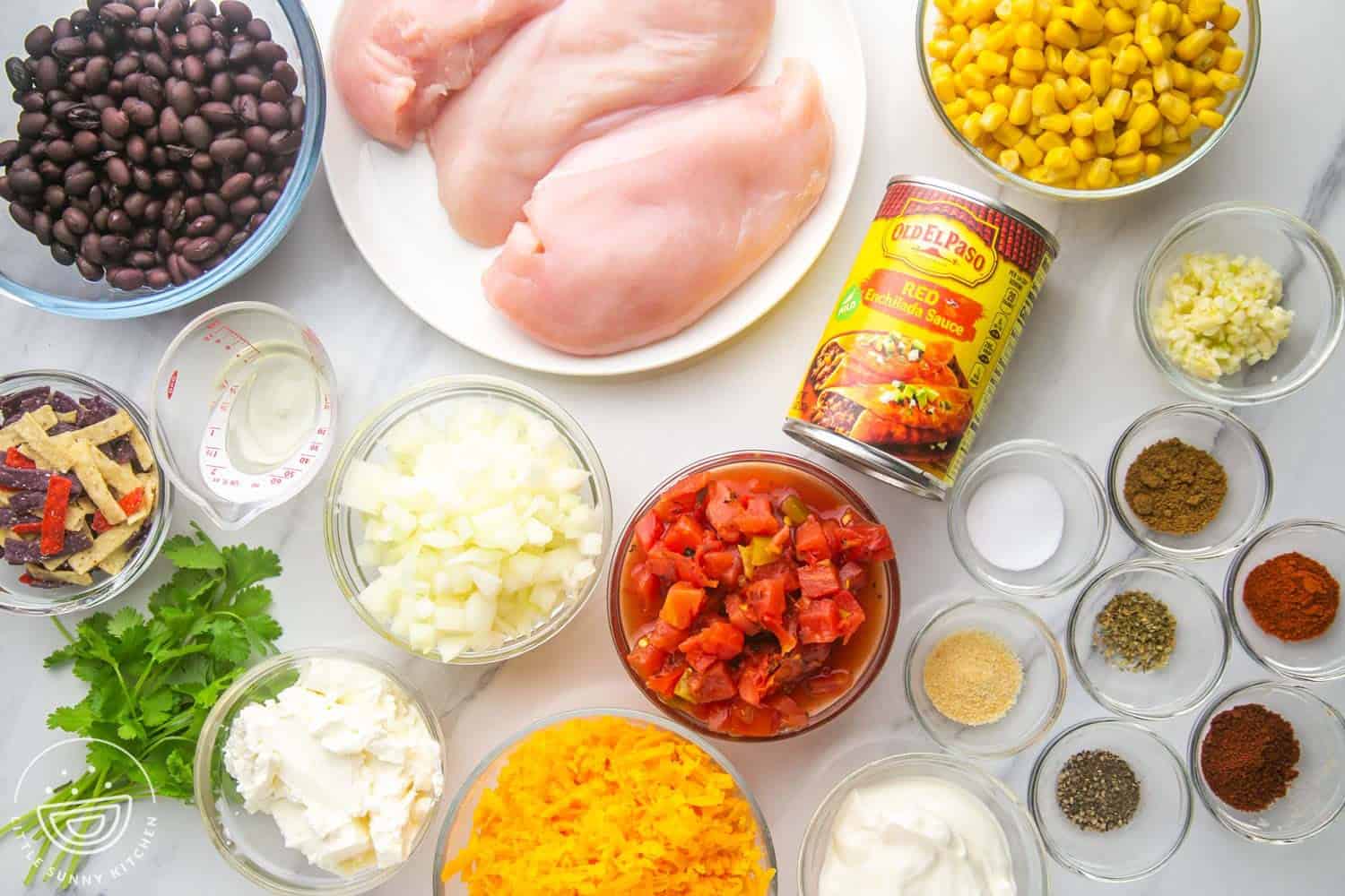 the ingredients needed to make chicken enchilada soup including rotel, beans, chicken, cheese, and corn.