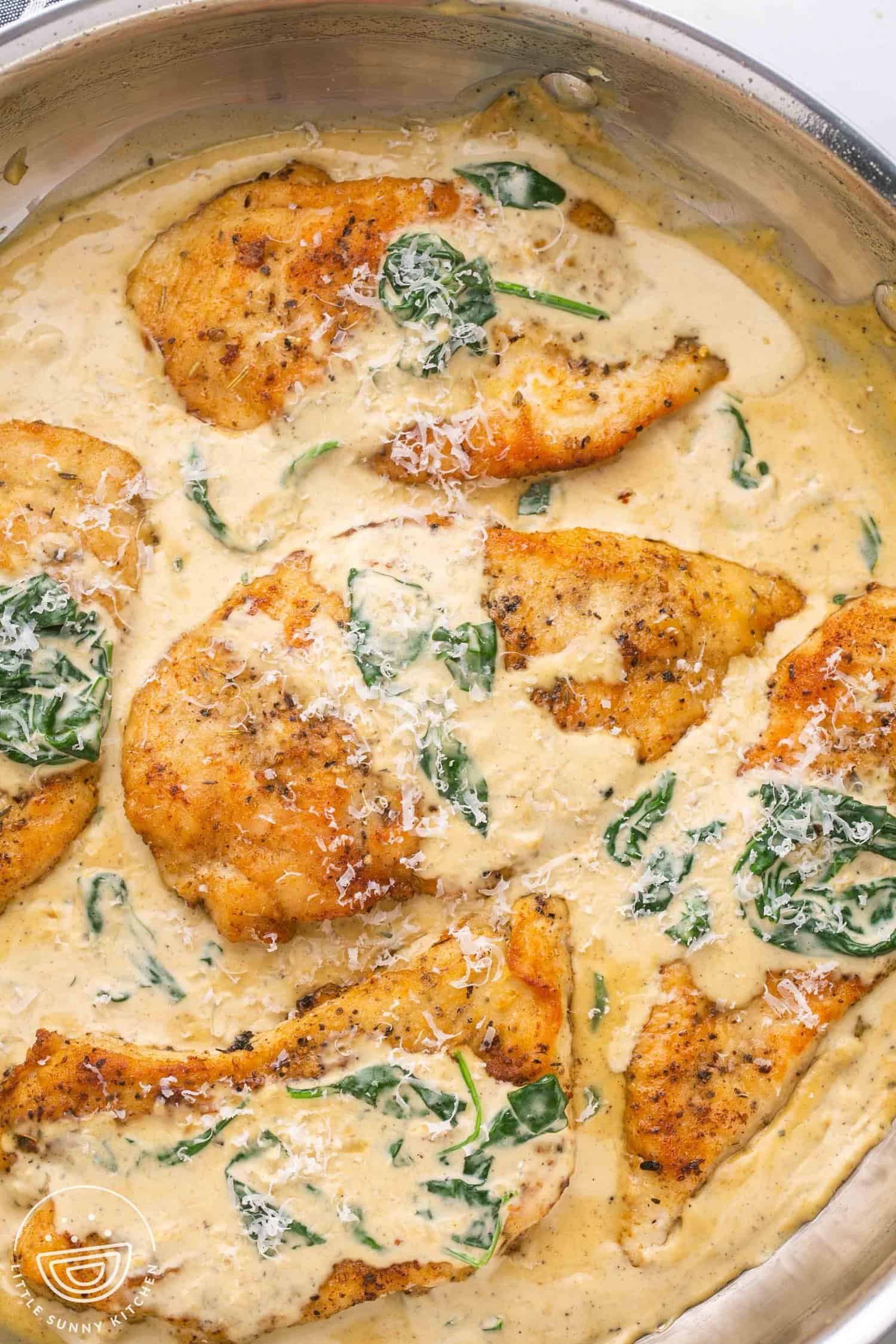 a metal skillet filled with creamy sauce and chicken florentine cutlets. Viewed from overhead.