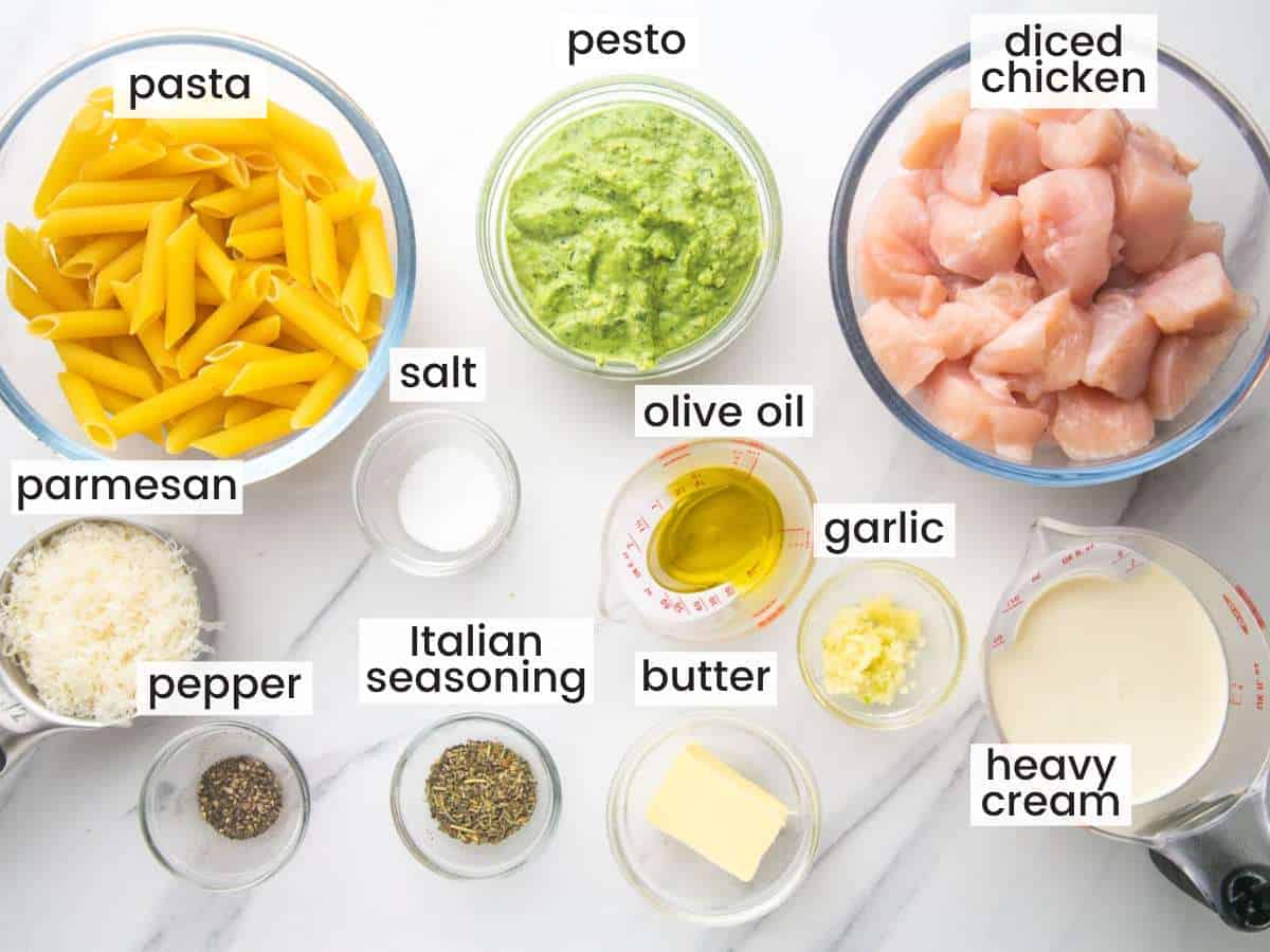 The ingredients needed to make pesto chicken pasta, all in separate bowls on the counter. Each ingredient in labeled with a text box.